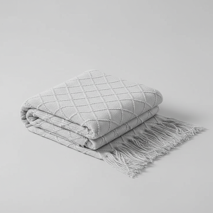 Folded gray blanket with tassels on a light gray background