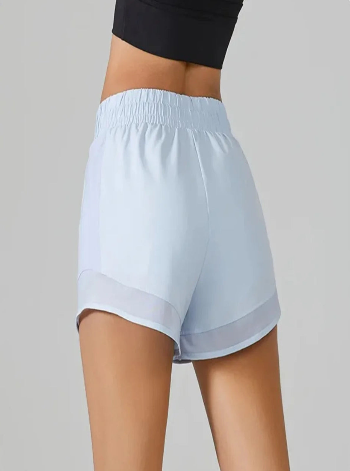 Light blue athletic shorts worn by a person on a gray background