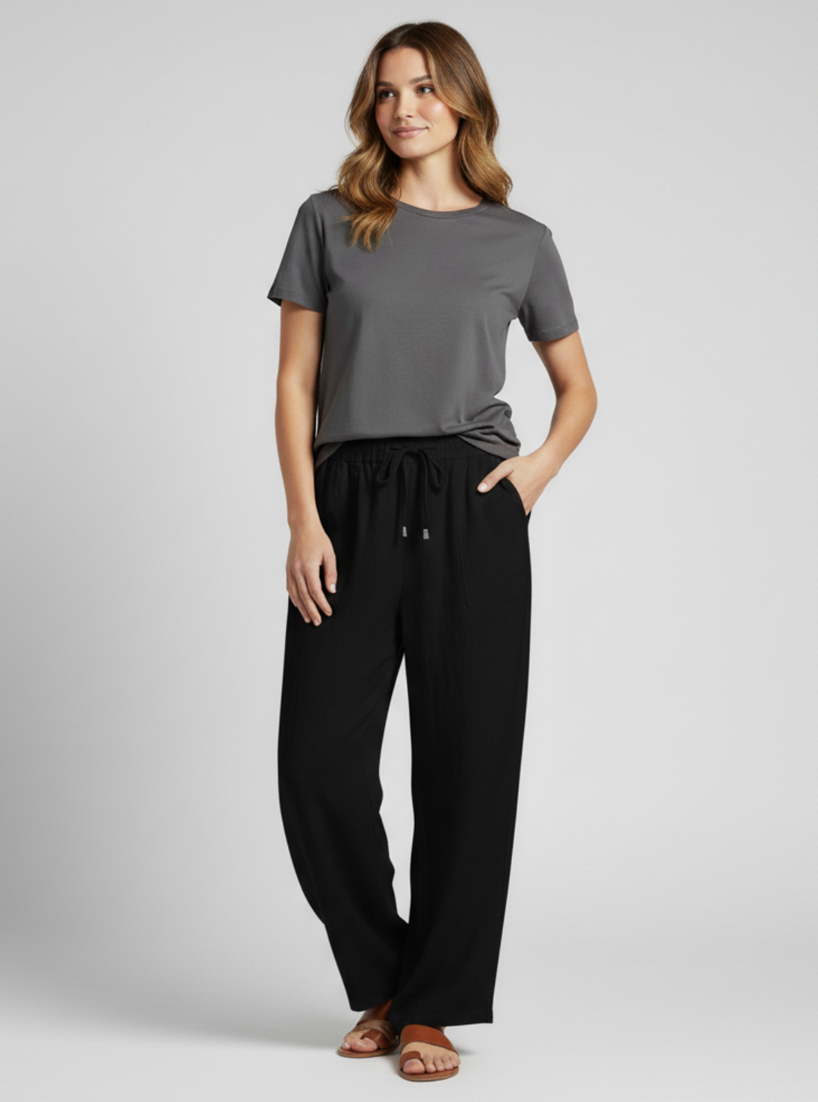Woman wearing a gray t-shirt and black pants on a light gray background