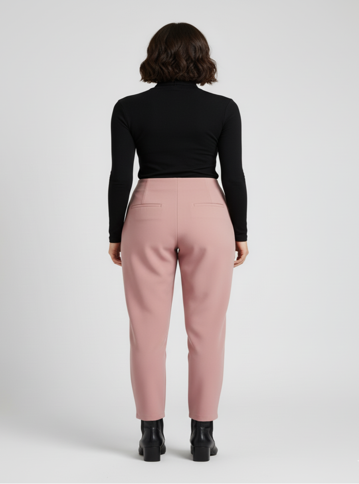 Person wearing a black top and pink pants on a white background