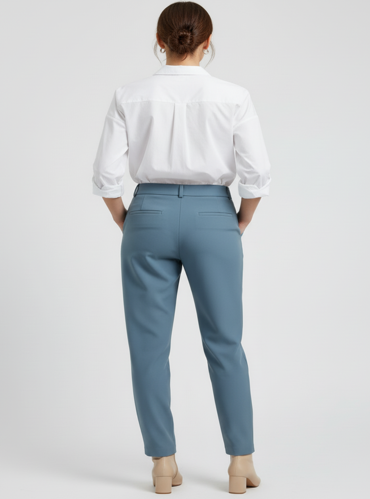 Person wearing a white shirt and light blue pants on a plain background