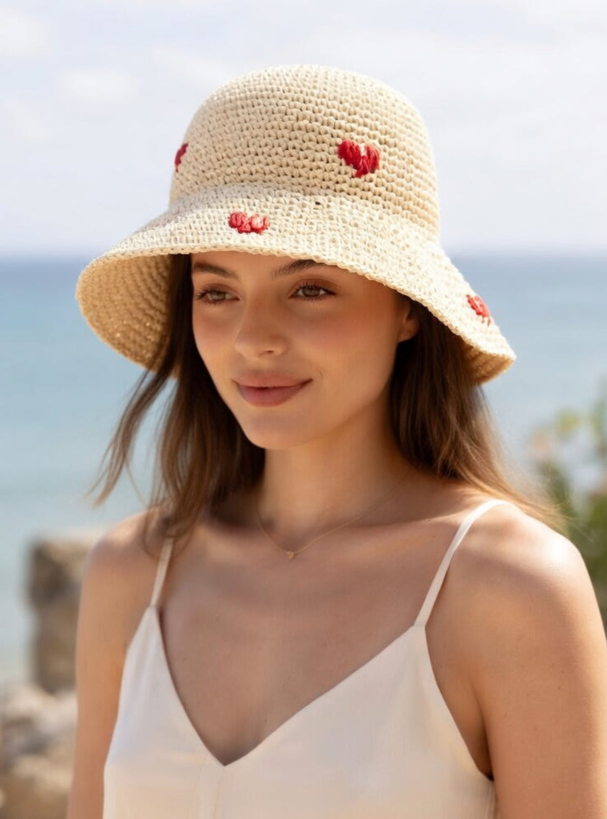 Woman wearing a straw hat with heart decorations at the beach