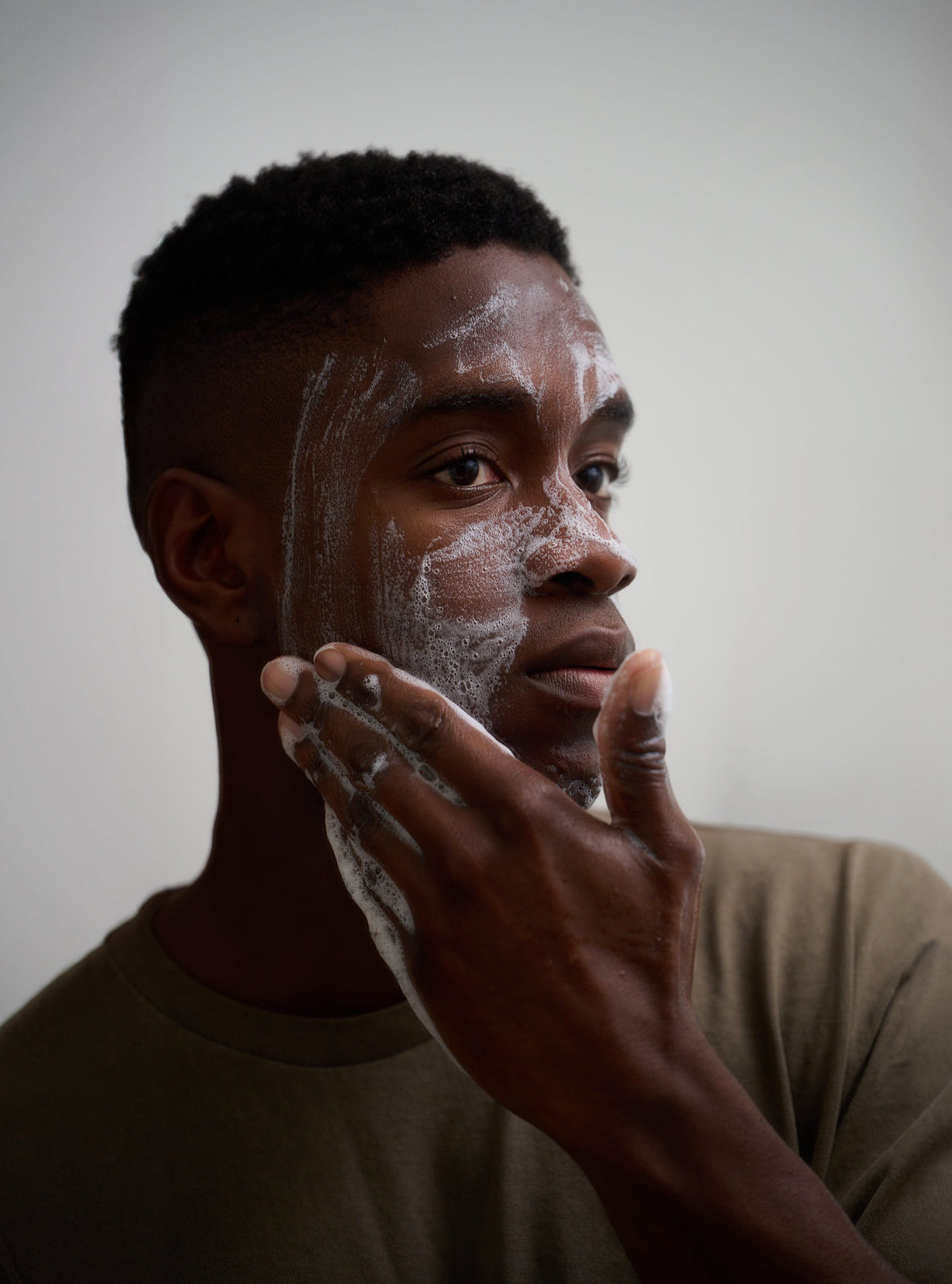 Man applying cream to his face against a plain background