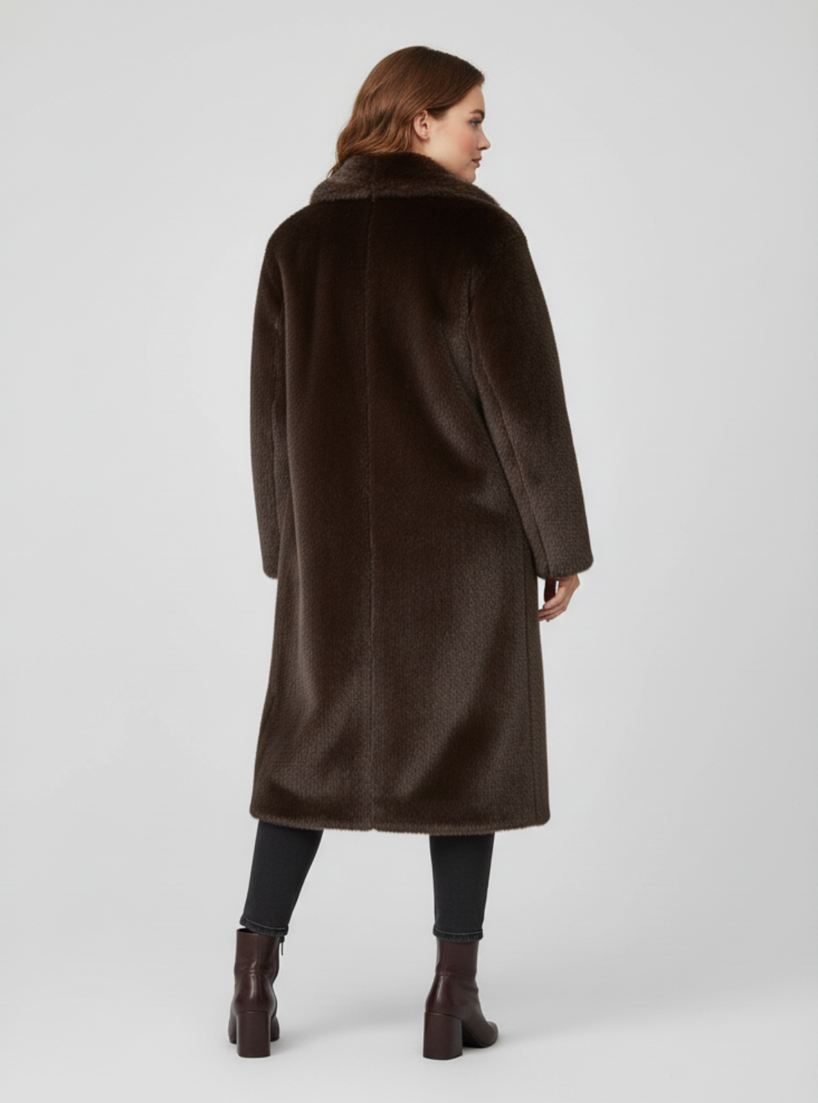 Woman wearing a long brown coat with fur collar on a white background