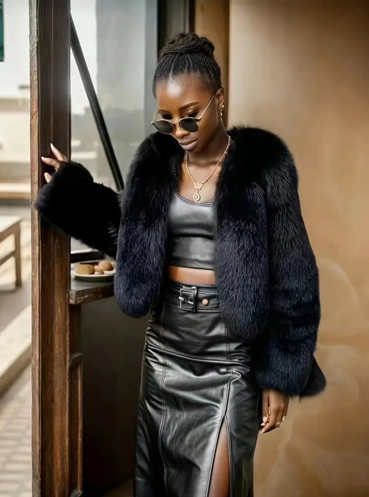 Woman wearing a black fur coat and leather outfit indoors.