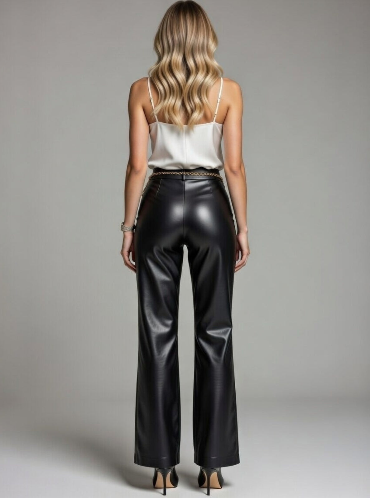 Woman wearing black leather pants and a white top against a gray background