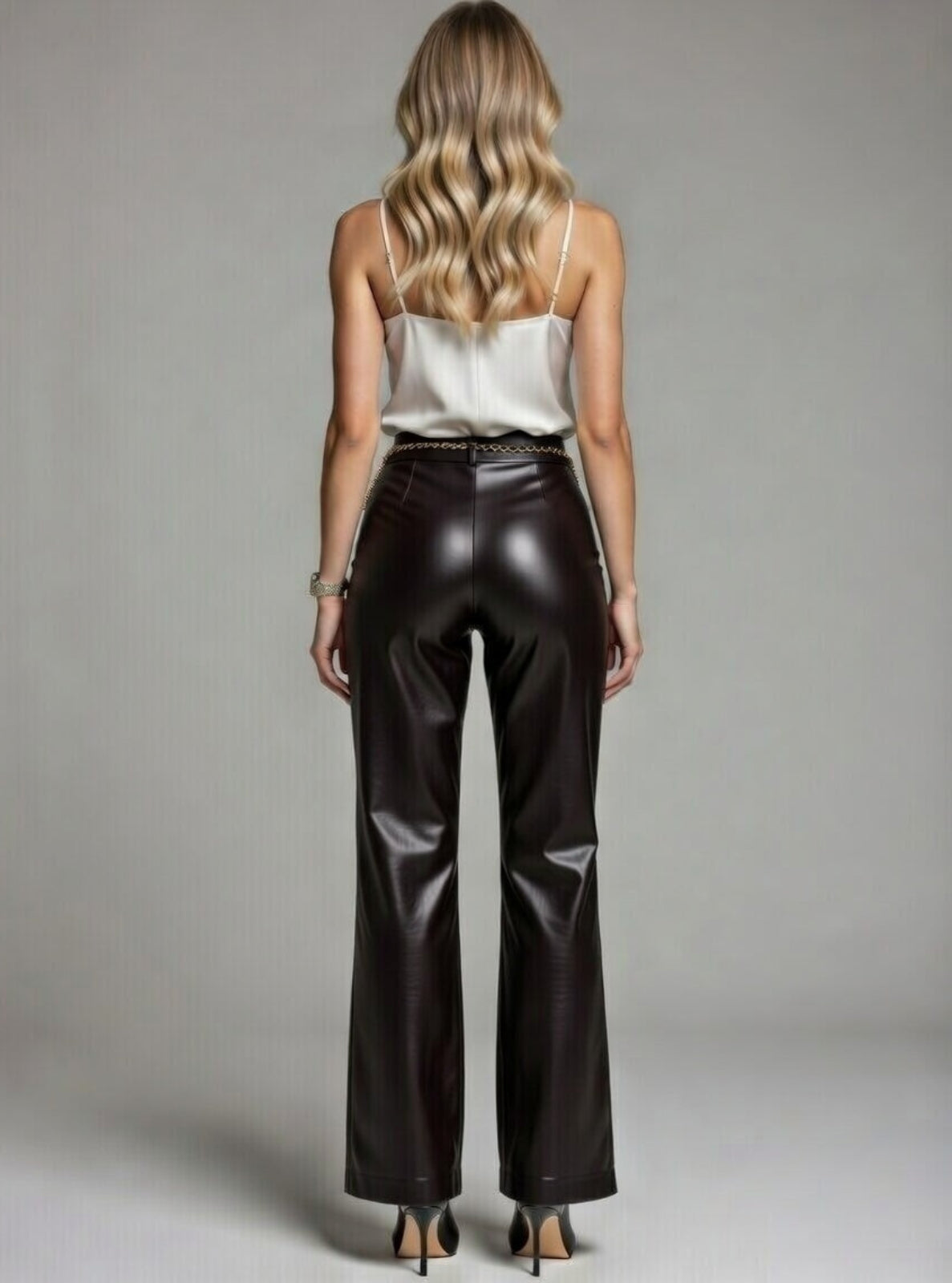Woman wearing a white top and black leather pants against a gray background