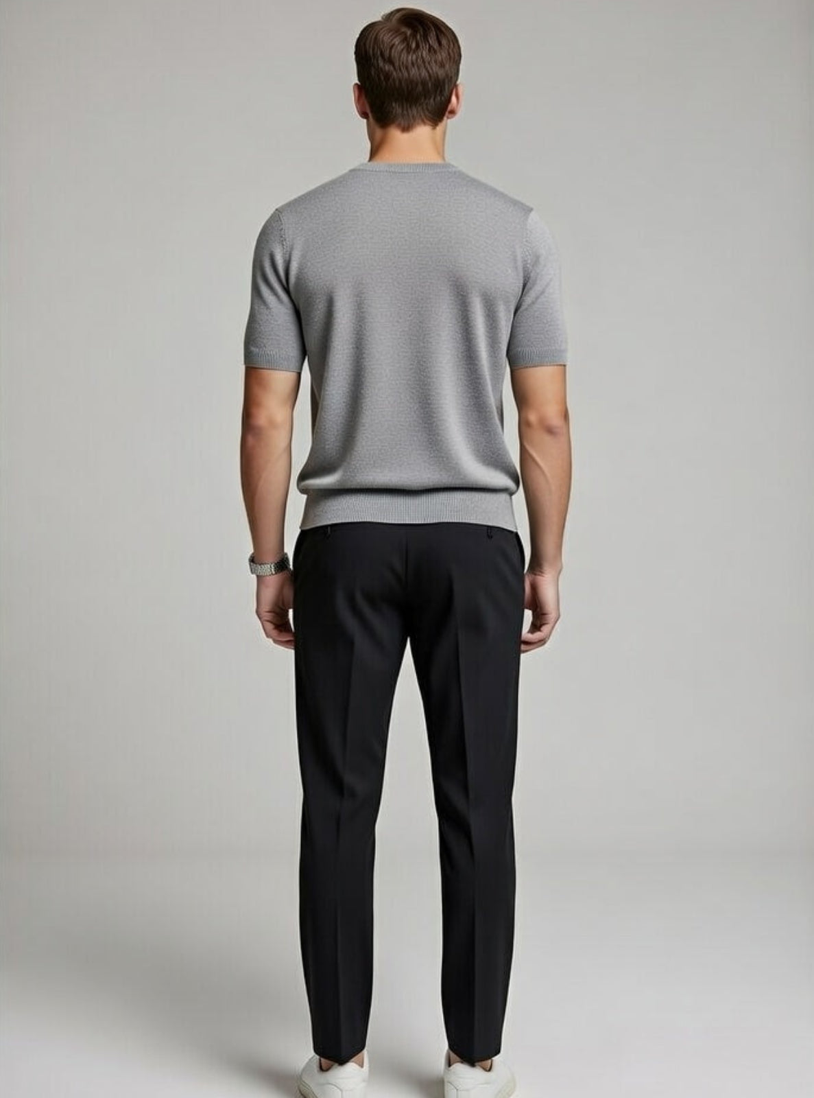 Man wearing a gray t-shirt and black pants on a plain background