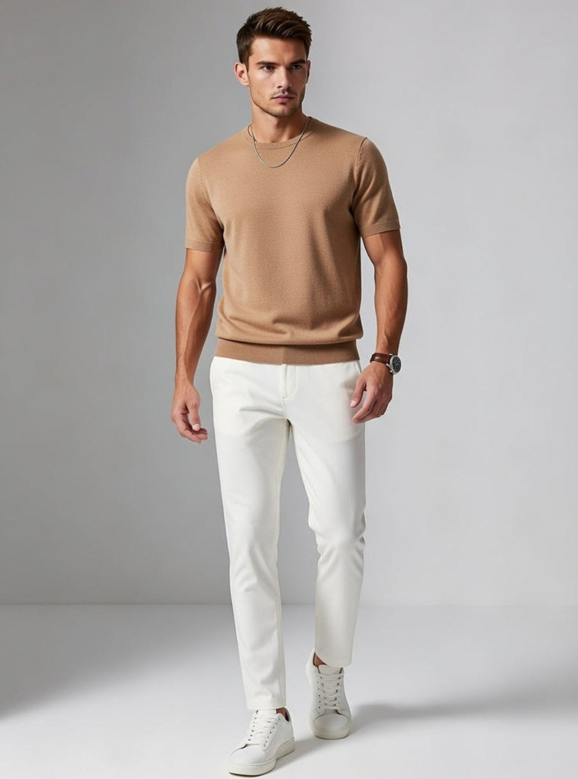 Man wearing a brown shirt and white pants against a gray background
