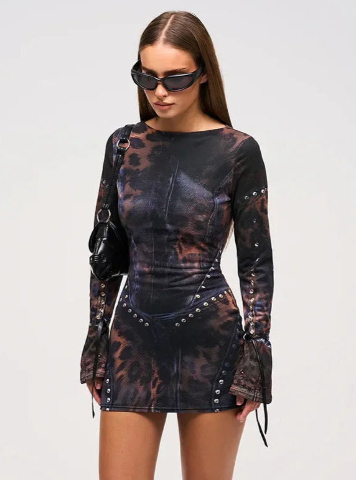 Woman wearing a patterned dress with long sleeves on a plain background