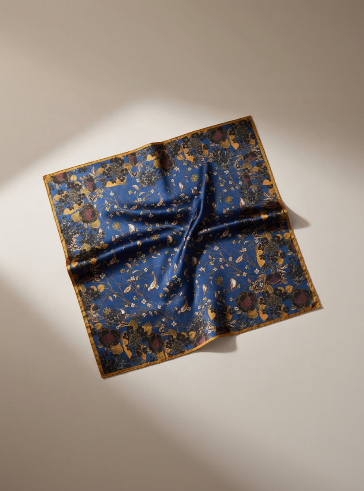 Folded blue fabric with gold patterns on a beige background