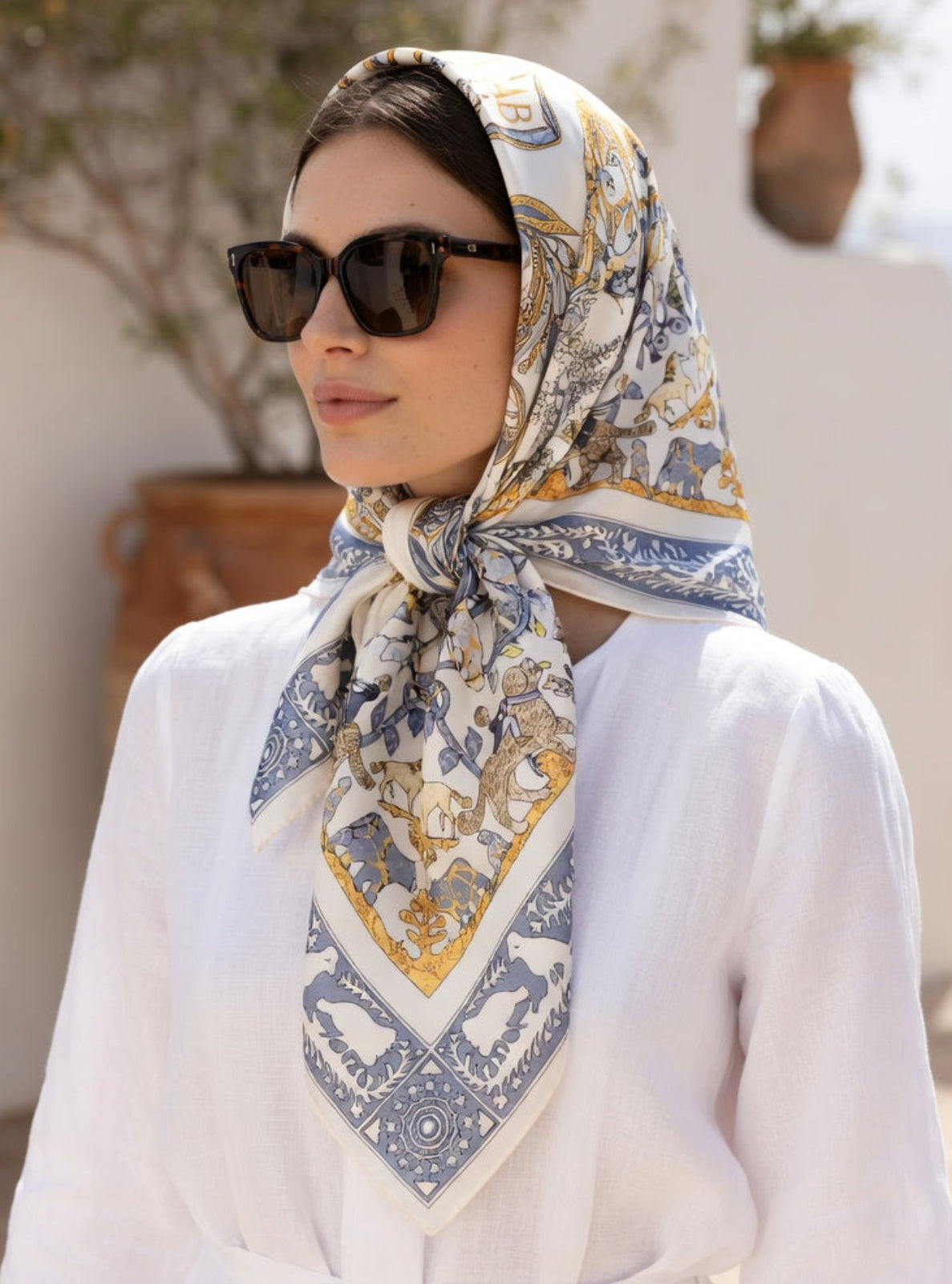 Woman wearing a patterned scarf and sunglasses outdoors
