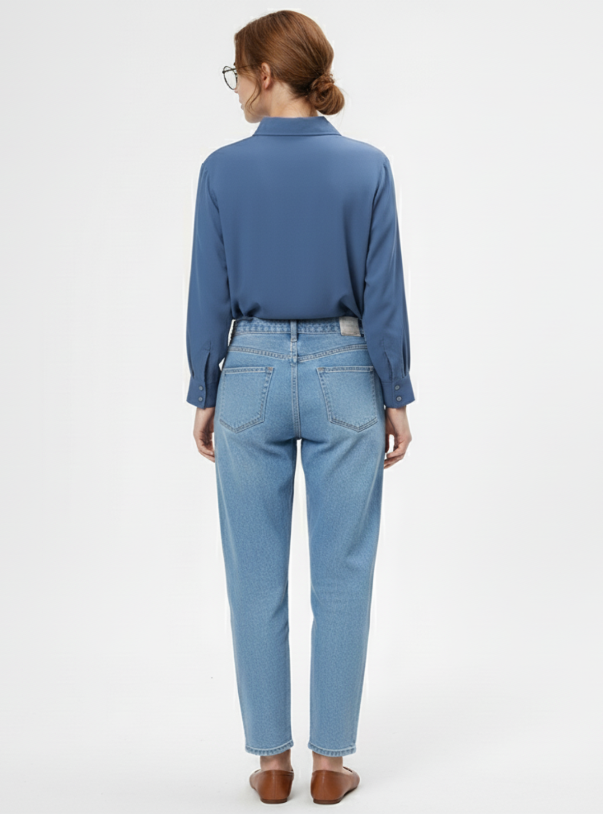 Person wearing a blue shirt and light blue jeans on a white background