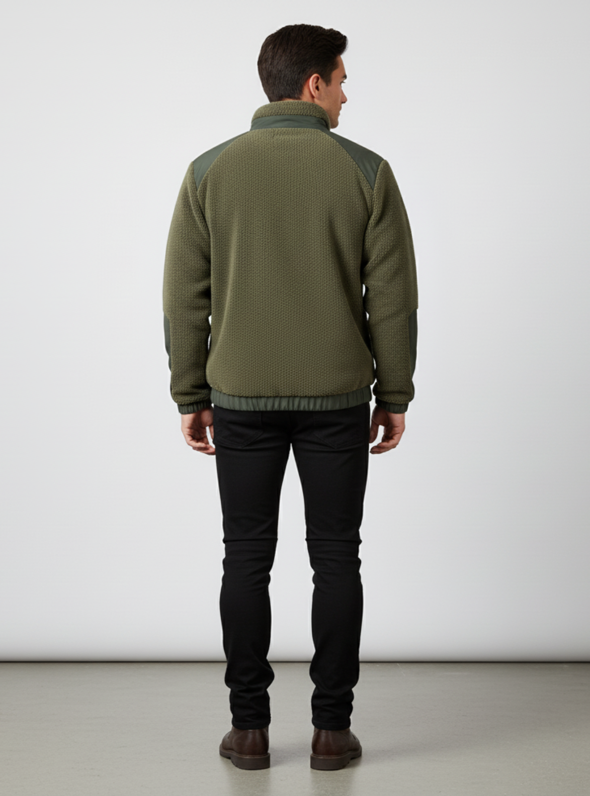 Man wearing a green jacket and black pants against a white background