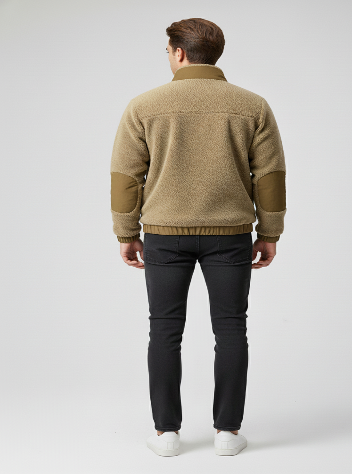 Man wearing a beige fleece jacket and black pants on a white background