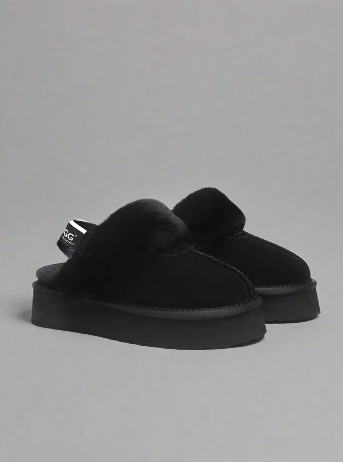 Black slippers with fur lining on a white background