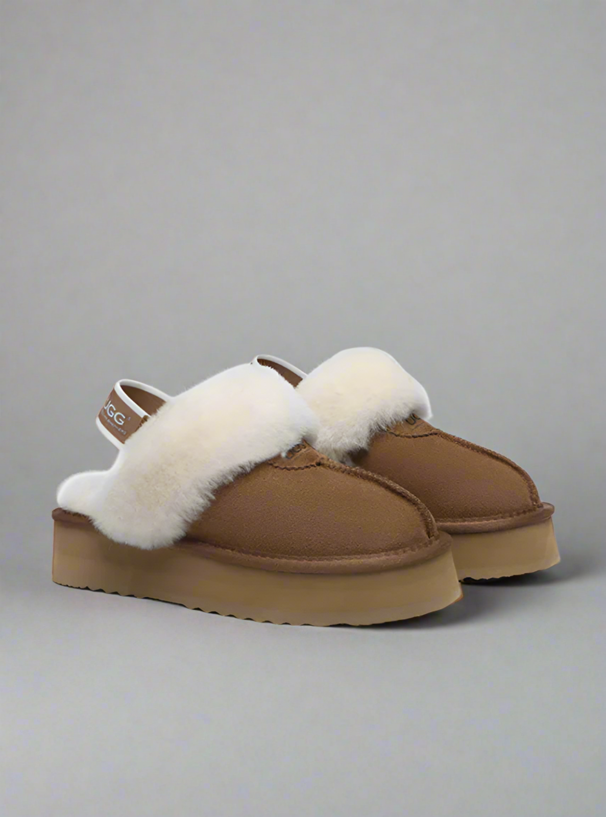 Pair of brown slippers with white fur trim on a gray background