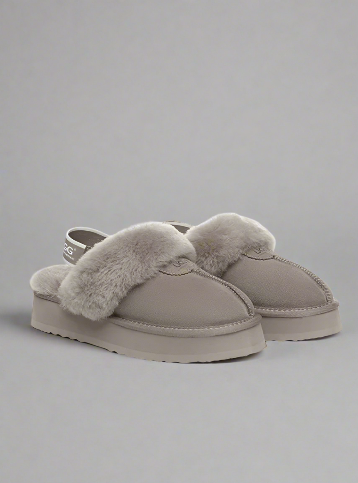 Pair of gray slippers with fur trim on a white background