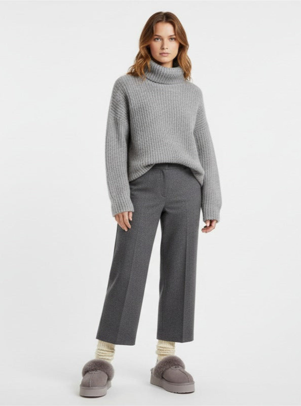 Woman wearing a gray sweater and pants on a white background