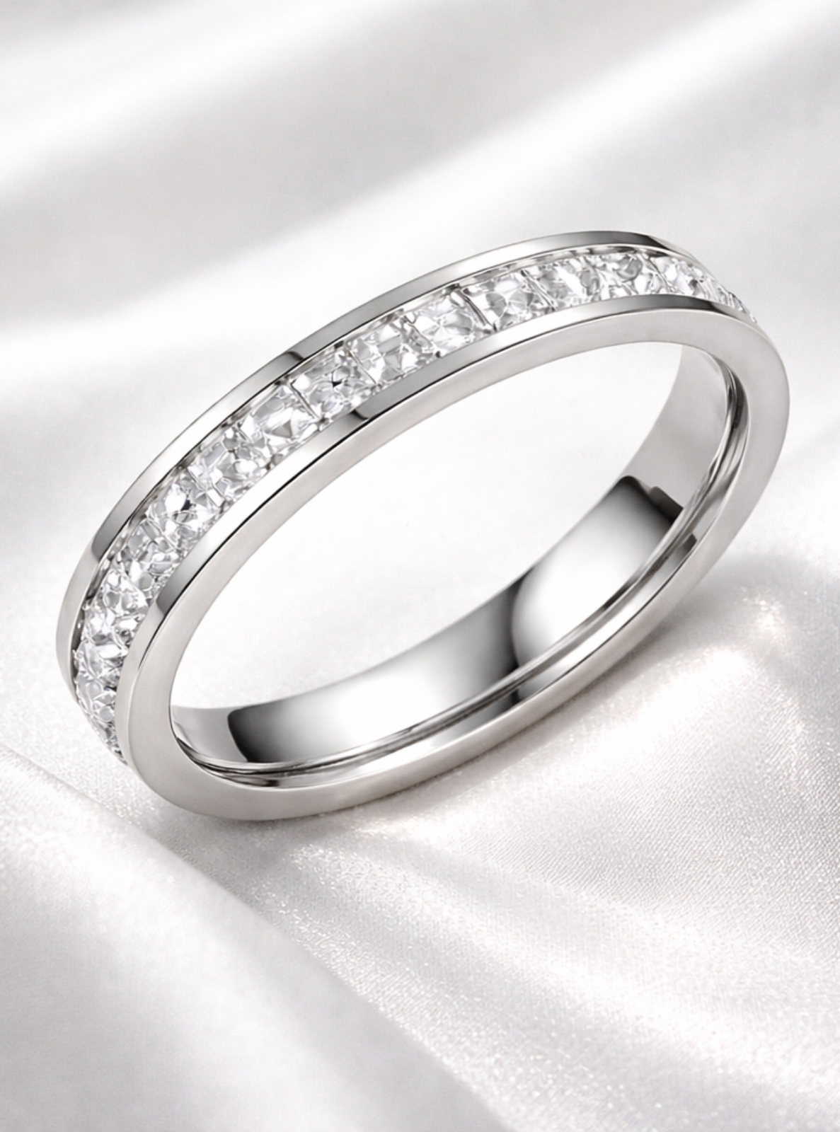 Silver ring with small diamonds on a white satin background