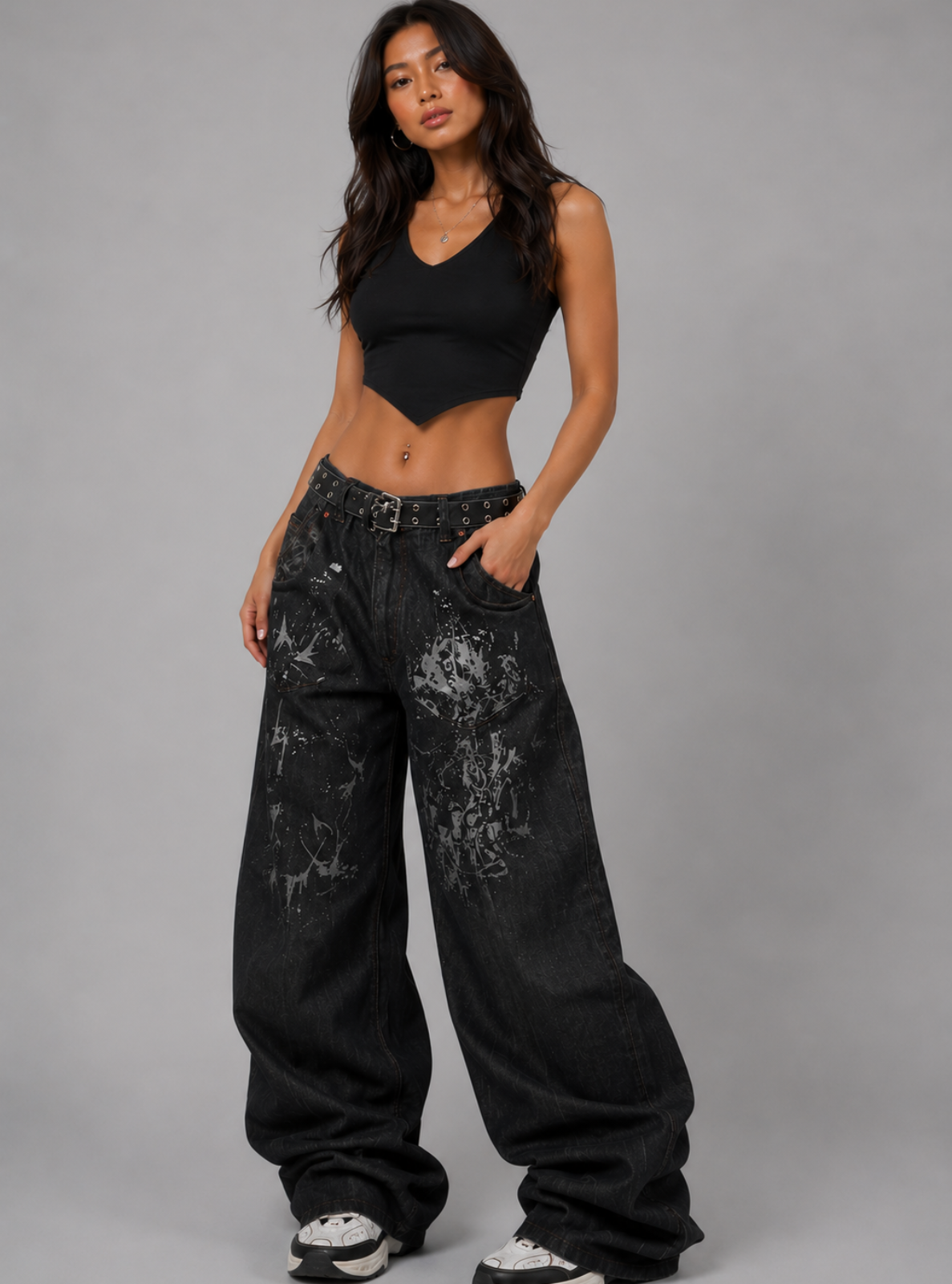 Woman wearing black distressed jeans and a black crop top on a gray background