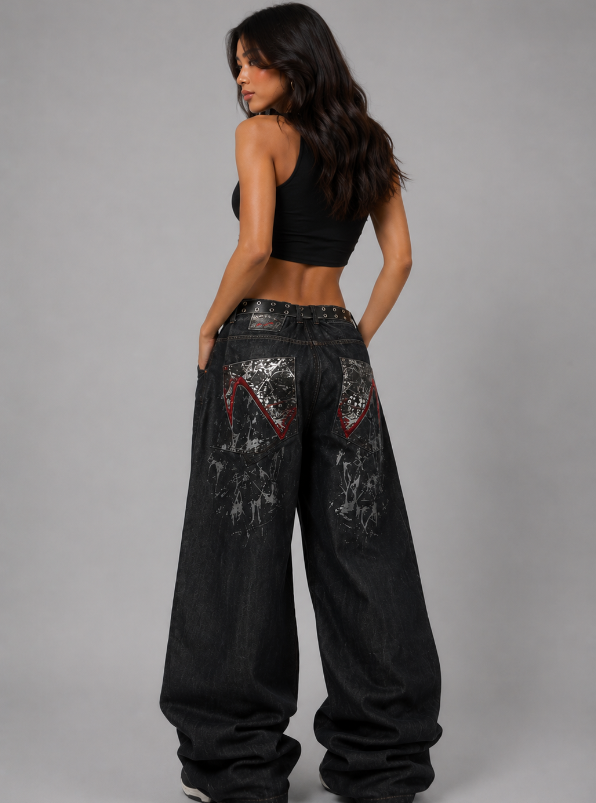 Woman wearing black distressed wide-leg jeans on a gray background
