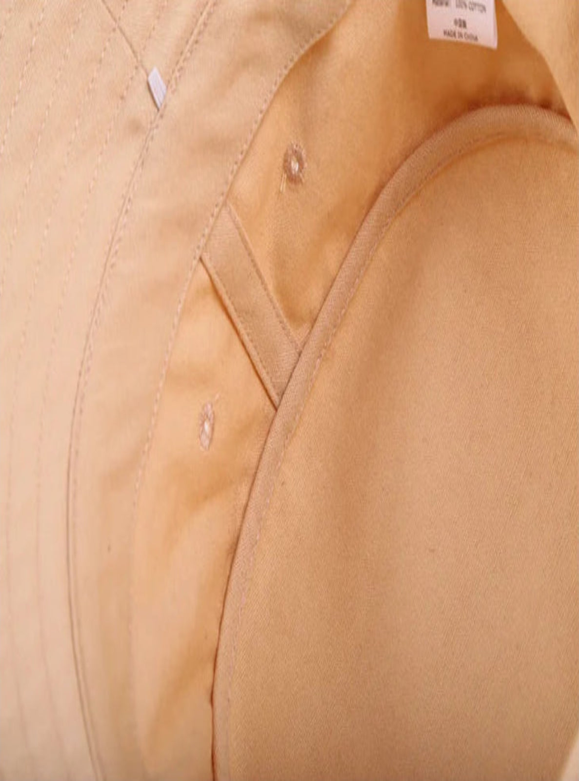 Close-up of a beige fabric with visible stitching and a label.