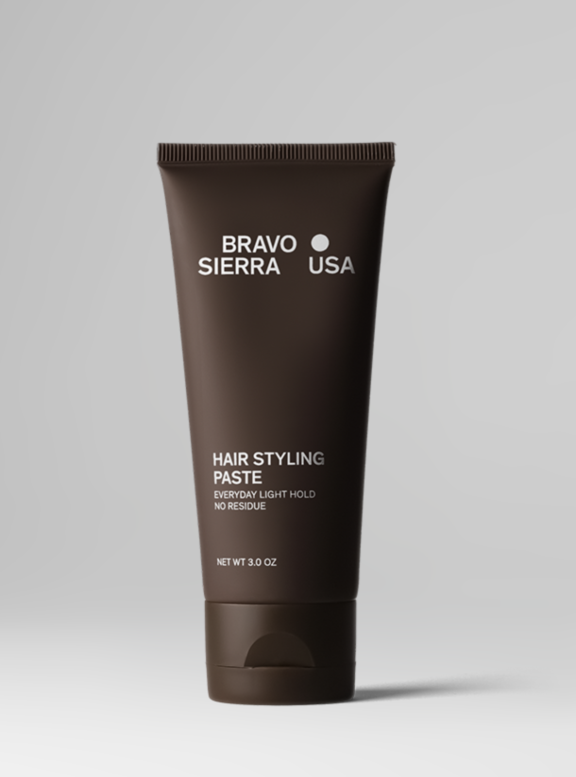 Brown tube of Bravo Sierra USA hair styling paste on a gray background