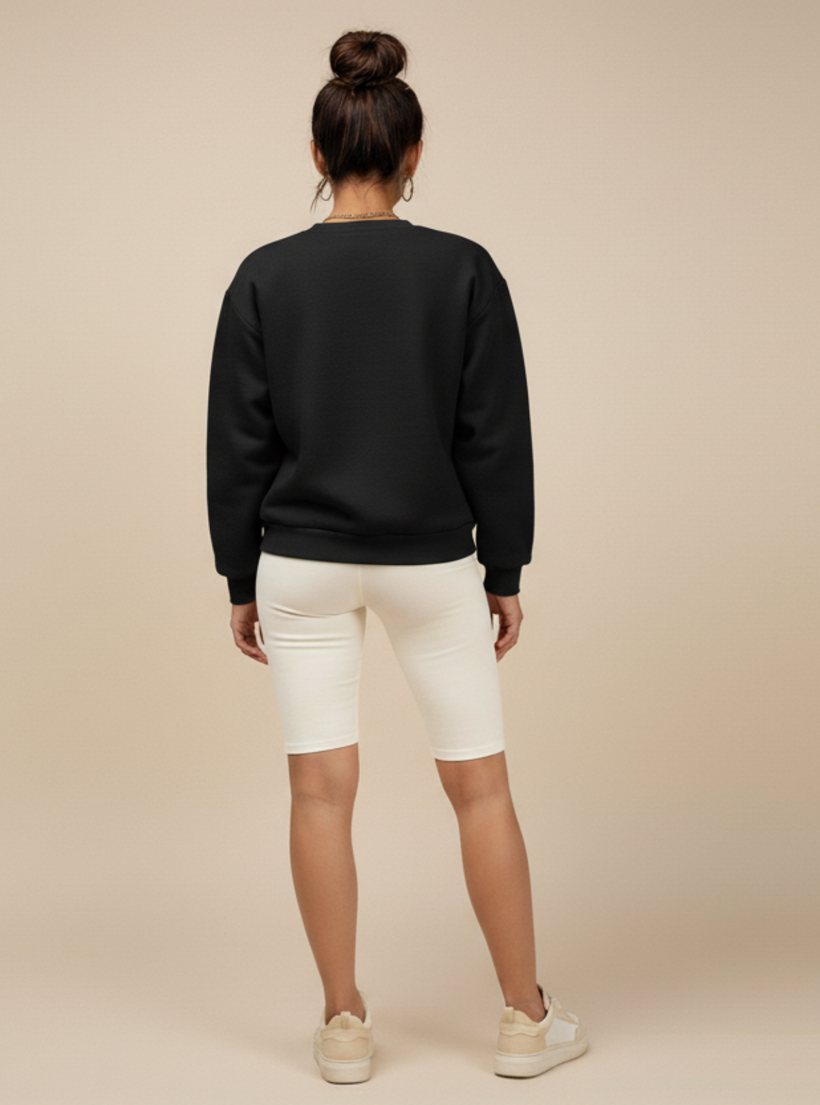Person wearing a black sweatshirt and white shorts on a beige background