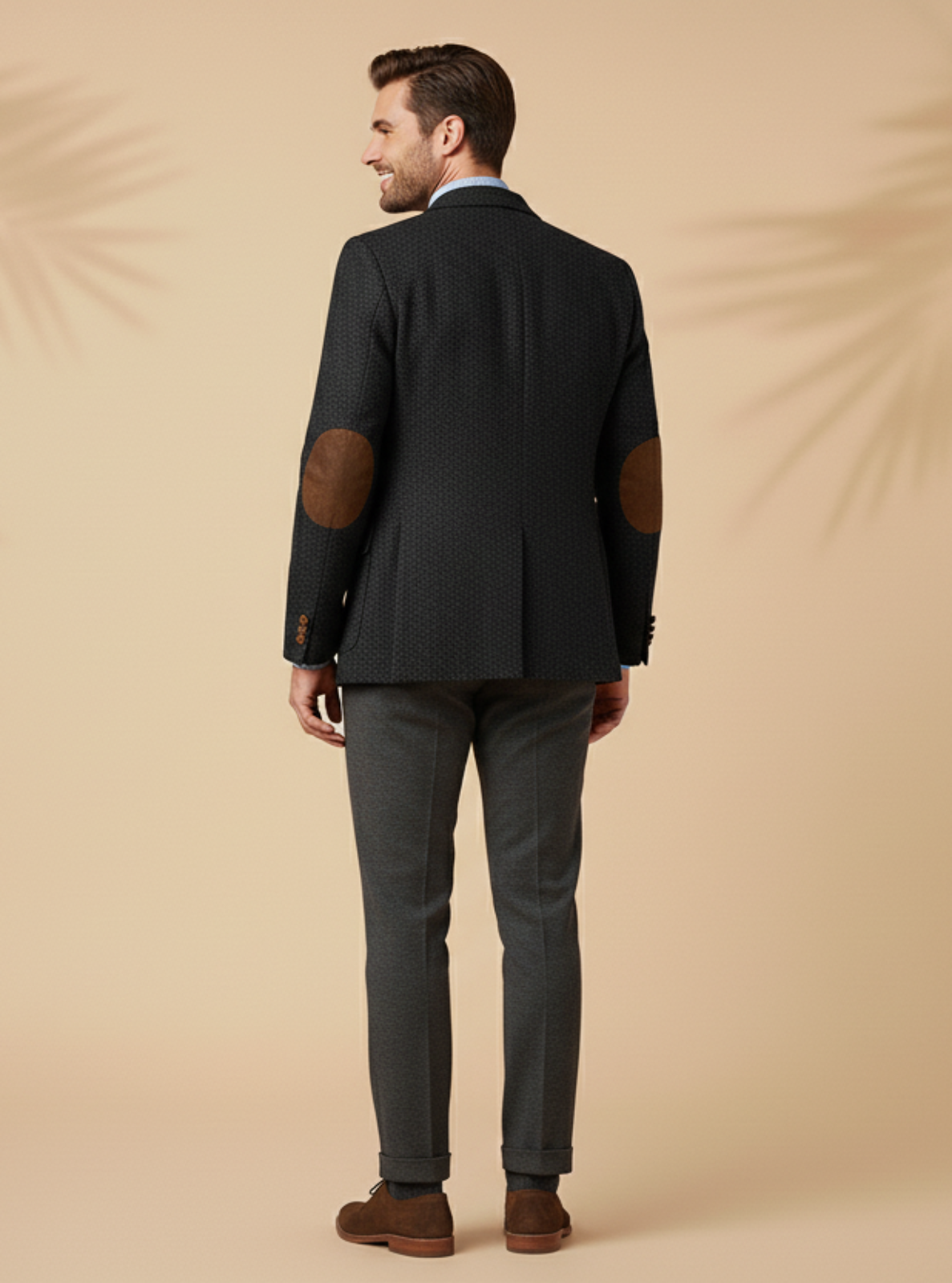 Man wearing a dark suit with elbow patches on a beige background