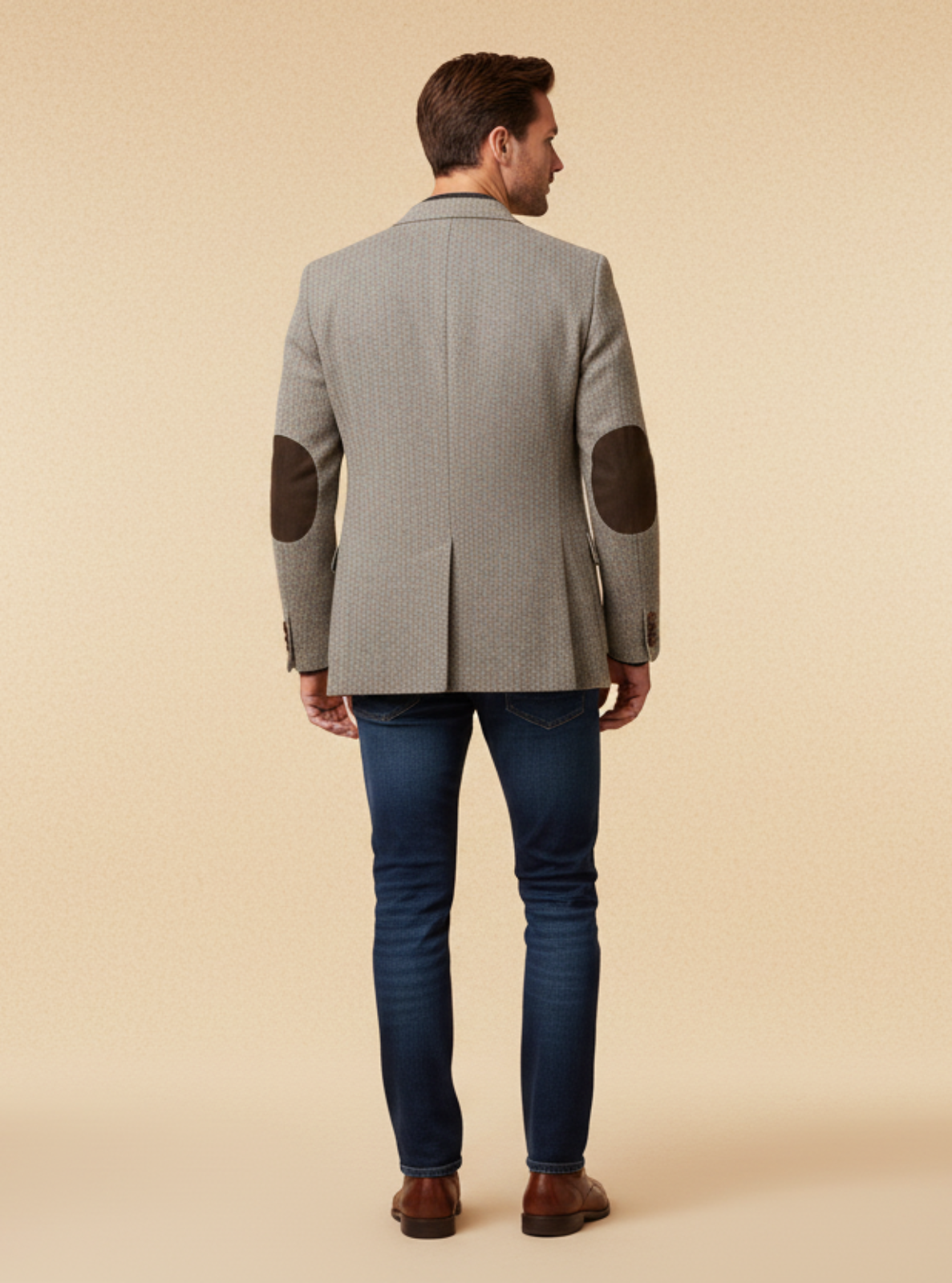 Man wearing a gray blazer with elbow patches on a beige background