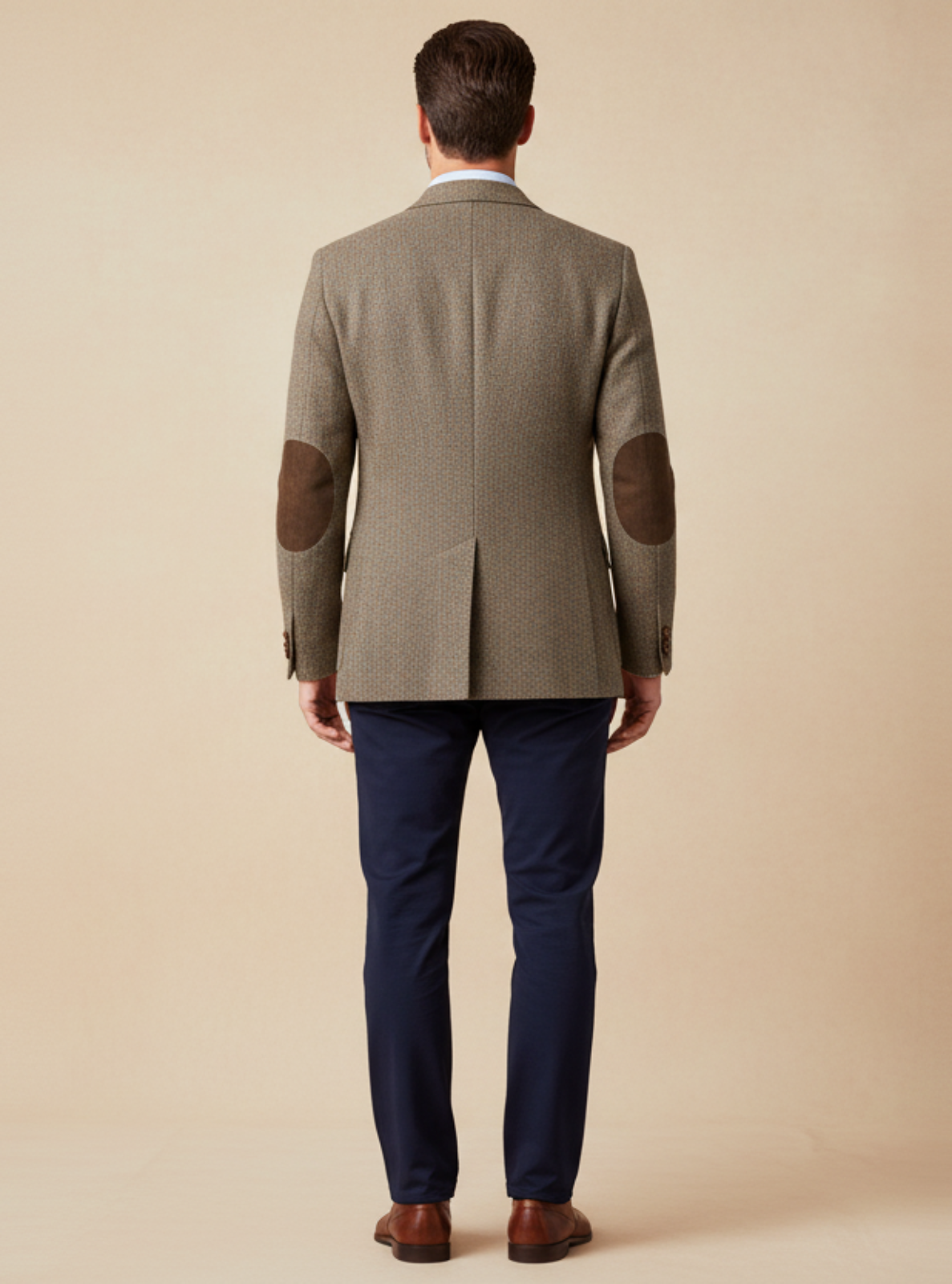 Man wearing a green jacket with elbow patches on a beige background