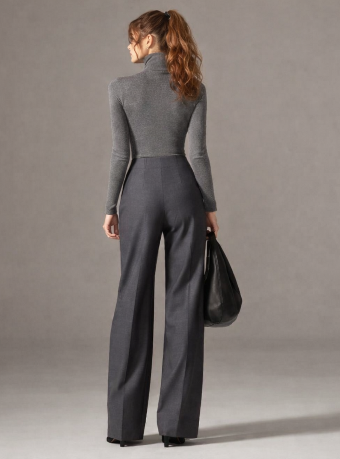 Woman wearing a gray outfit with wide-leg pants against a plain background