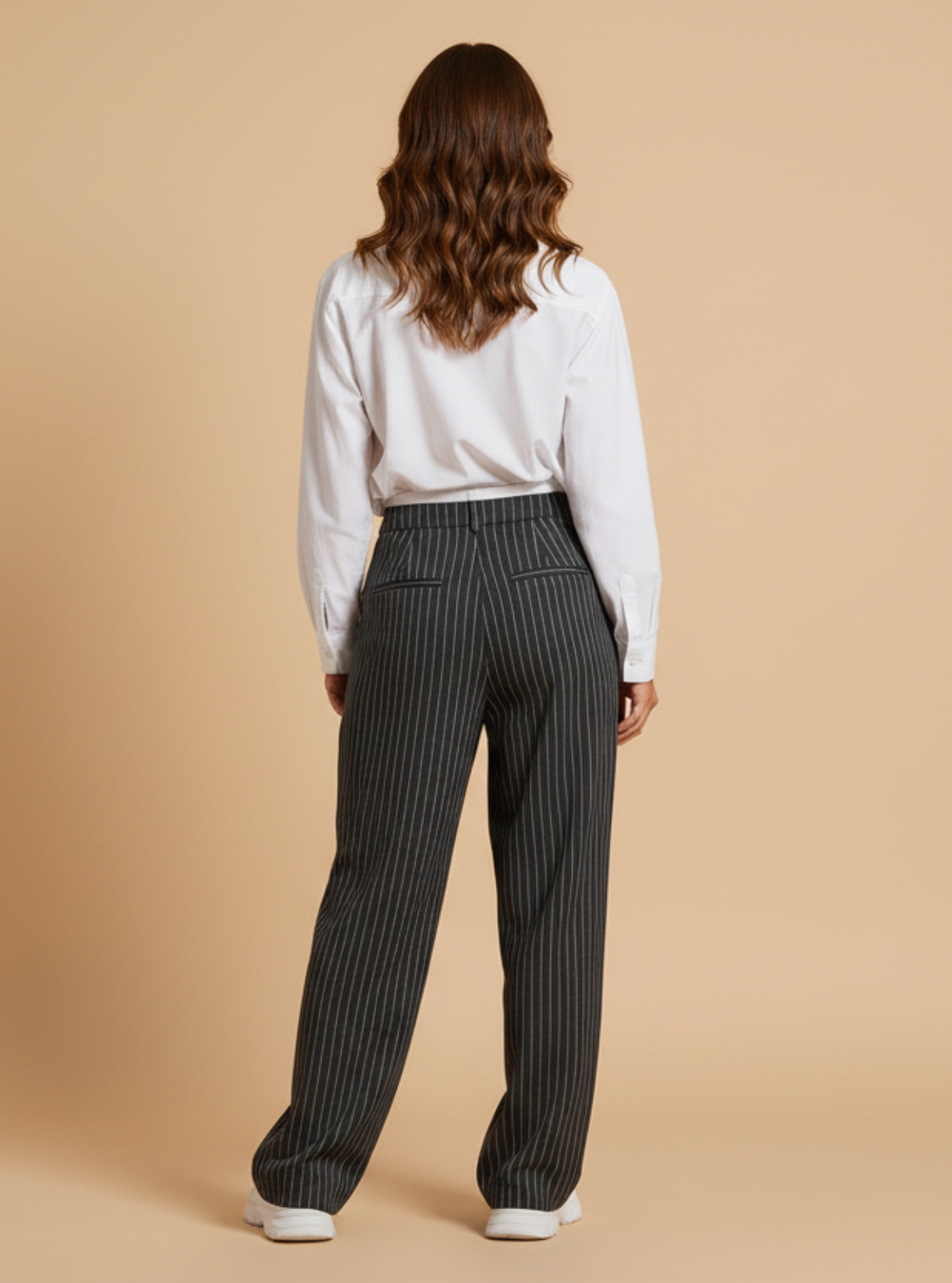 Person wearing a white shirt and black pinstripe pants on a beige background