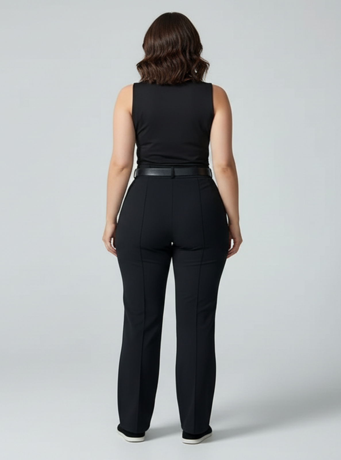 Woman wearing a black sleeveless top and pants on a gray background