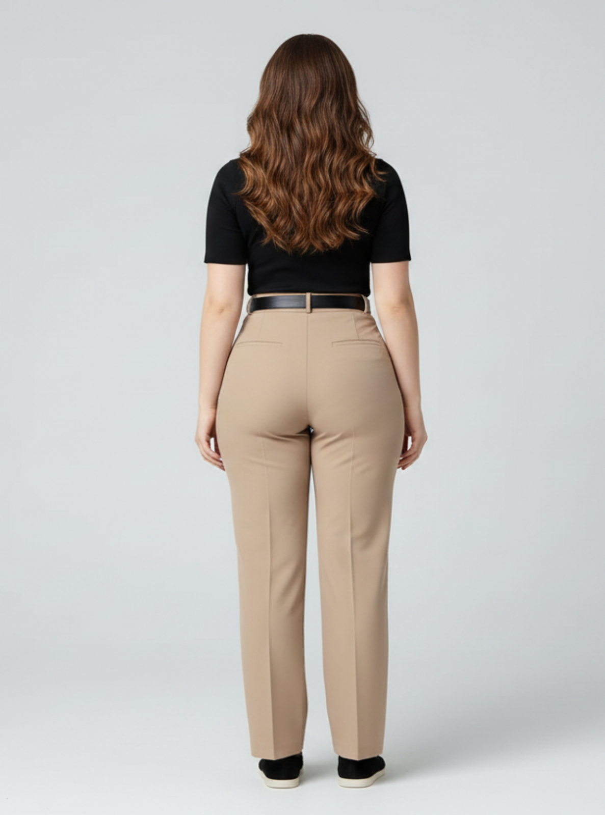 Woman wearing beige pants and a black top on a white background