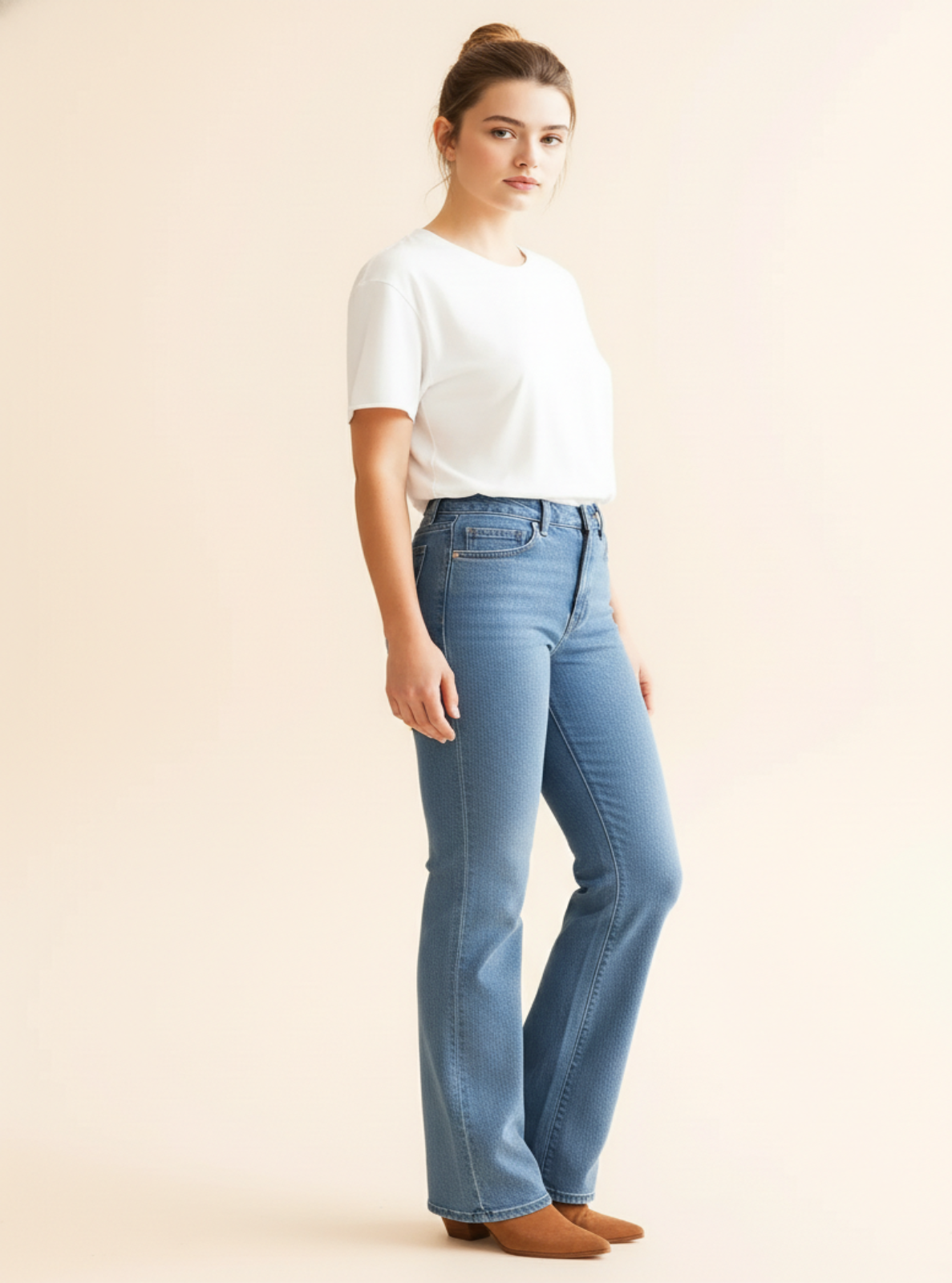 Woman wearing a white t-shirt and blue jeans against a plain background