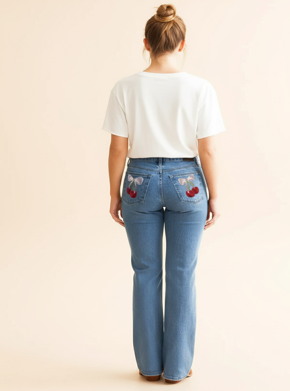 Person wearing blue jeans with floral patches on a beige background