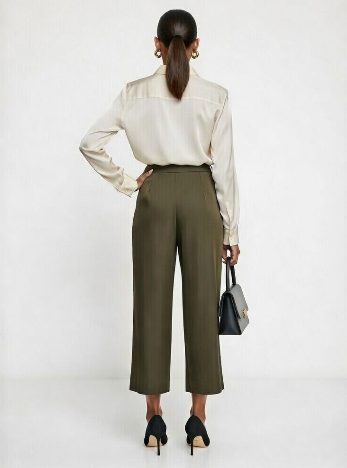 Woman wearing a white blouse and olive green pants on a white background