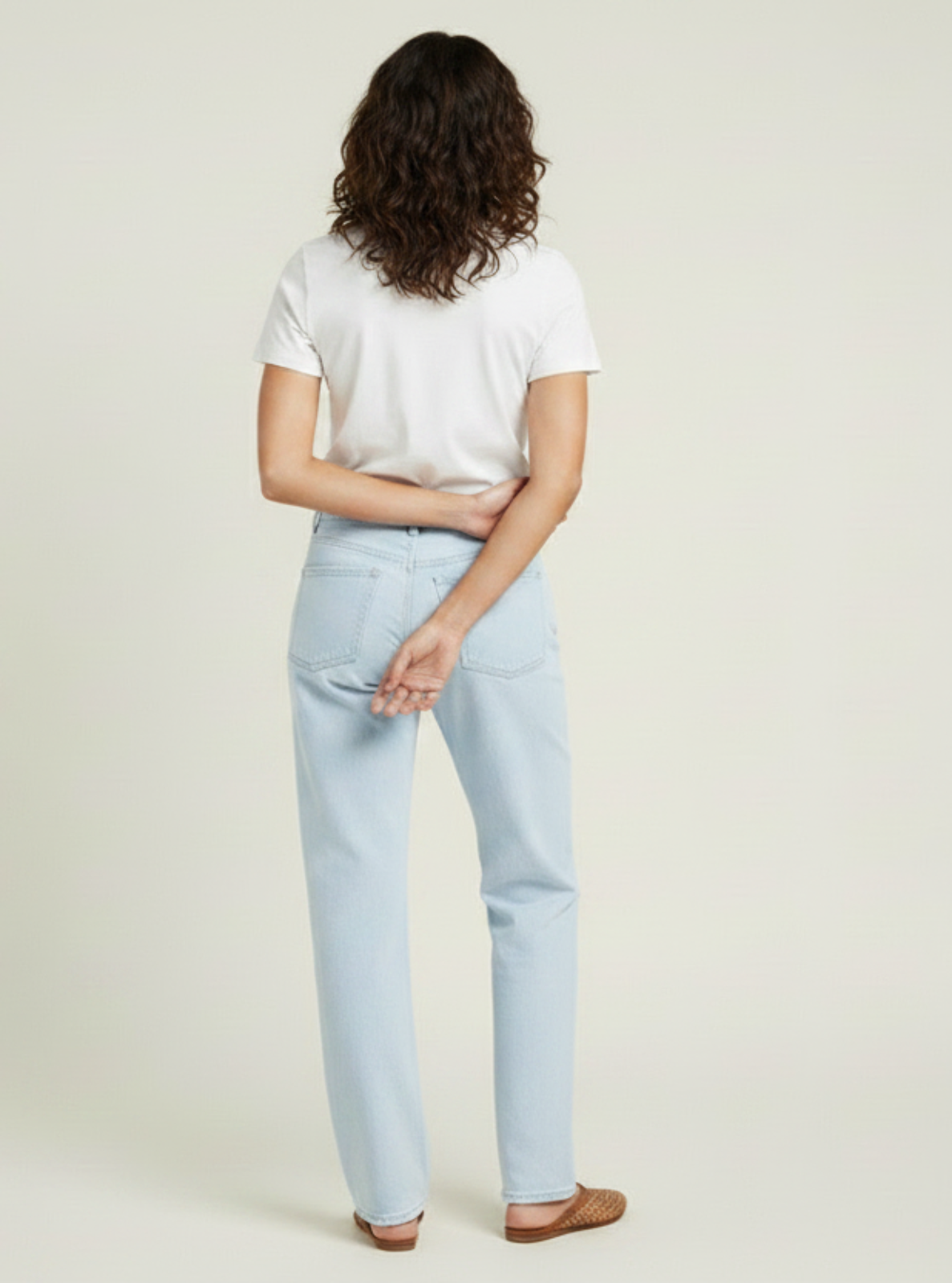 Person wearing a white t-shirt and light blue jeans on a plain background