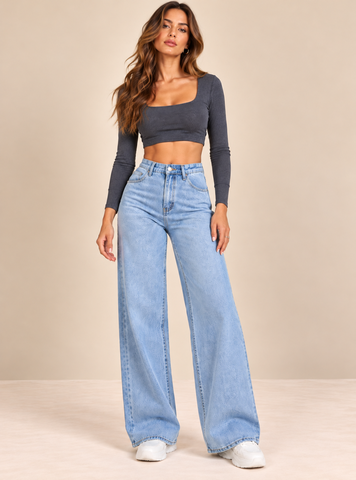 A woman modeling a dark gray long-sleeve crop top and light blue high-waisted wide-leg jeans against a solid beige studio background.