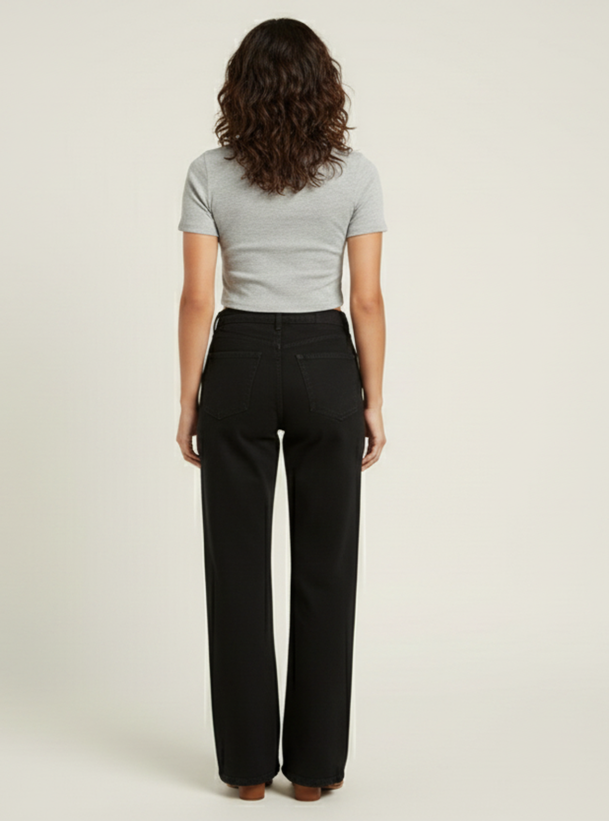 Woman wearing a gray t-shirt and black pants on a beige background