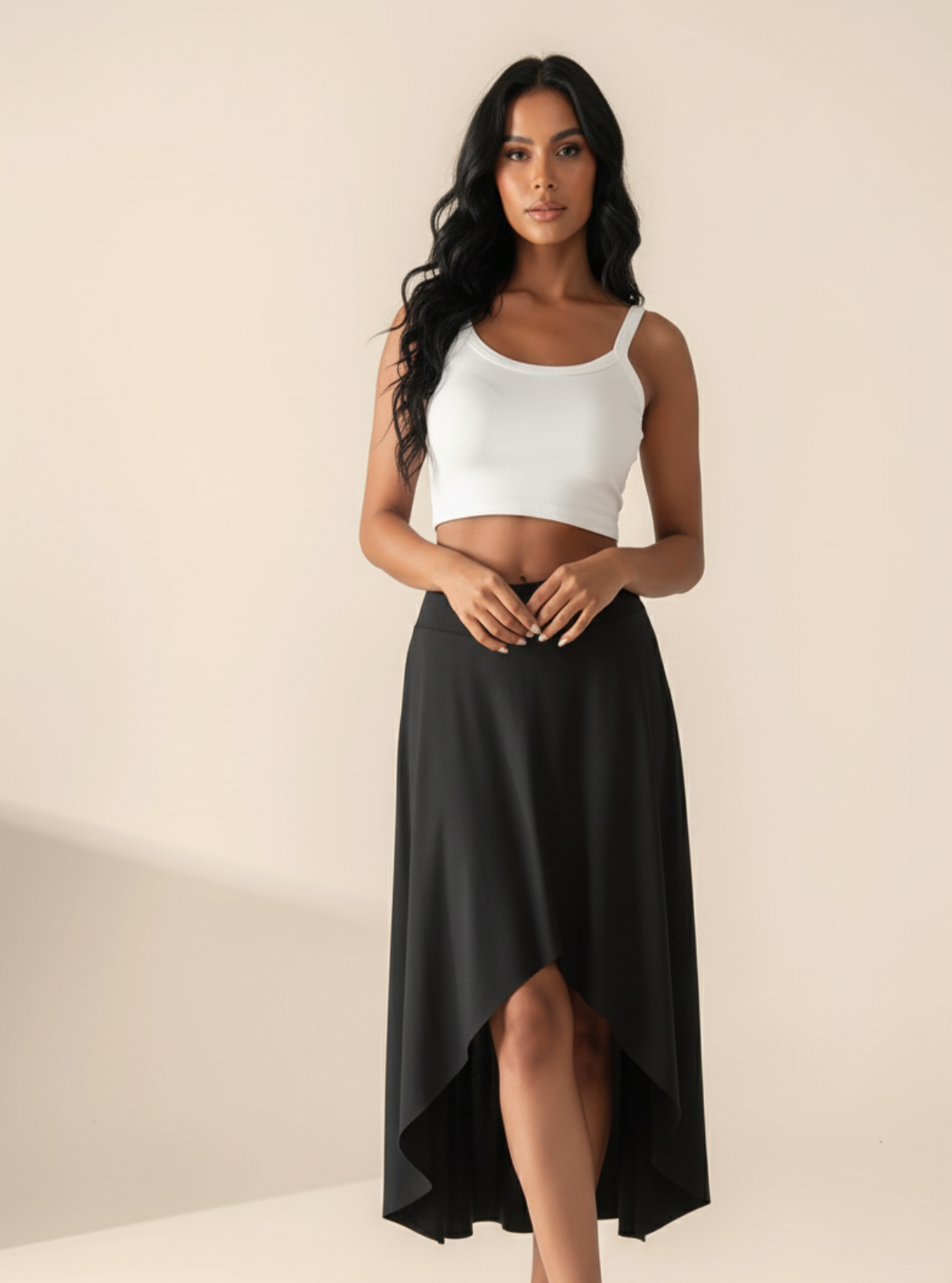 Woman wearing a white crop top and black skirt on a beige background