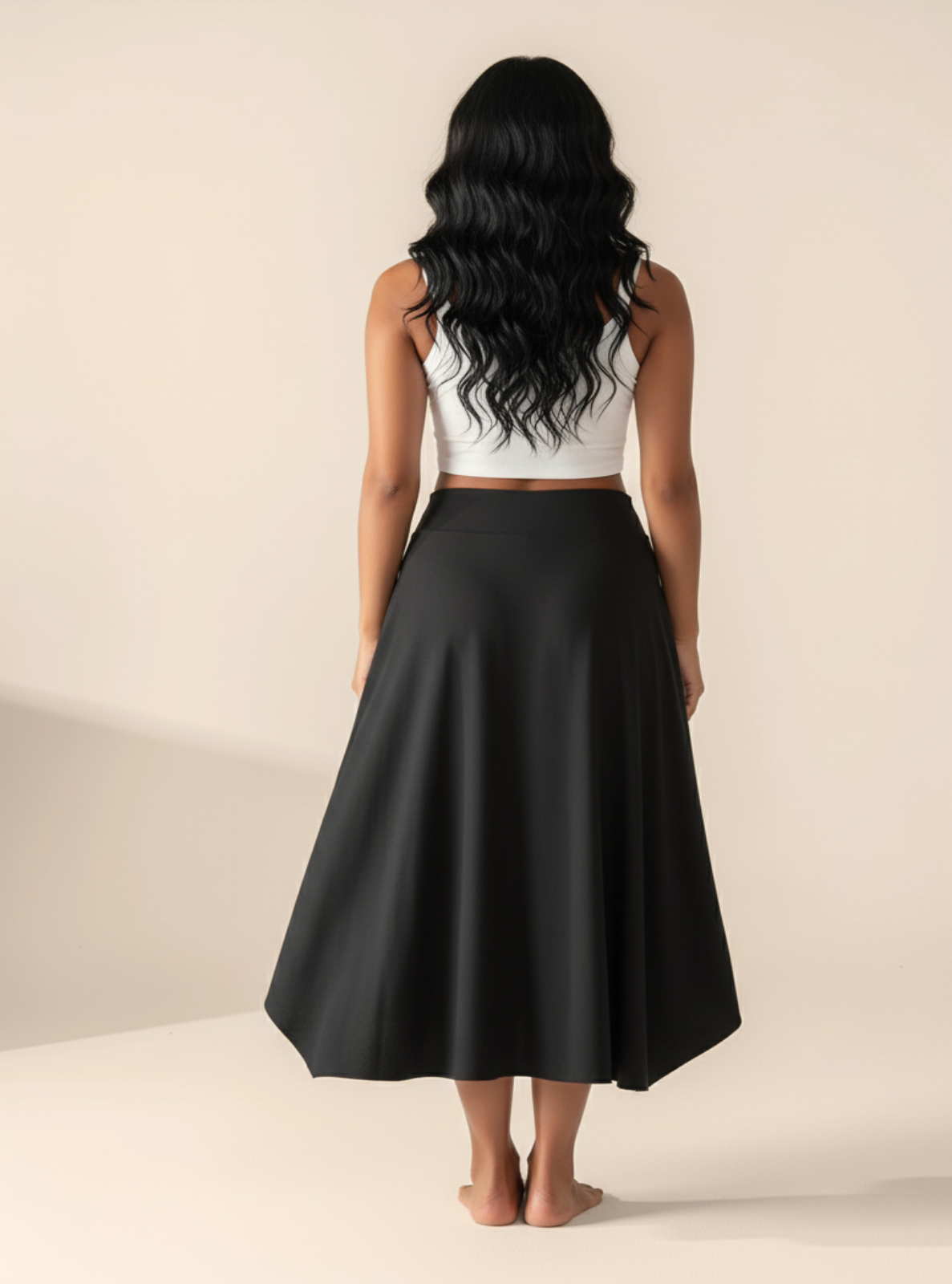 Woman wearing a white crop top and black skirt on a beige background