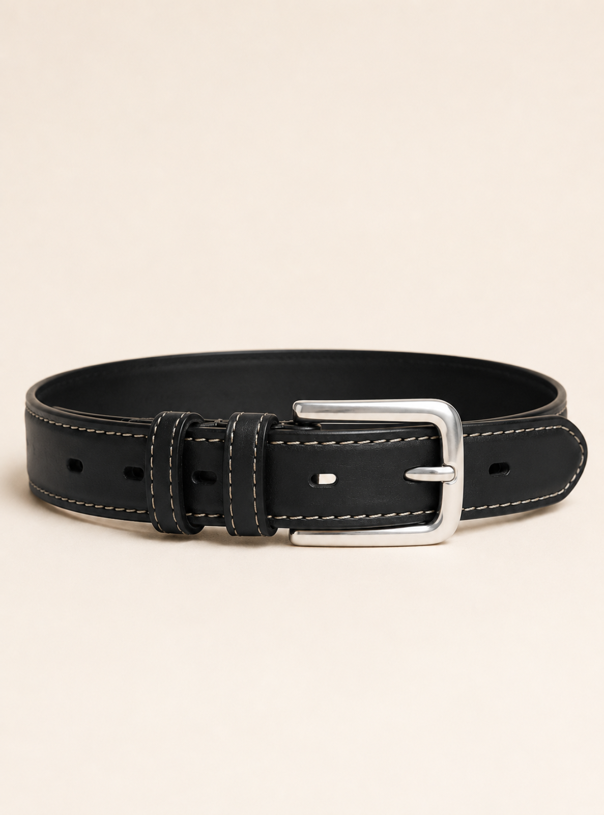 A black leather belt with white contrast stitching and a polished silver-tone metal buckle, presented on a light beige background.