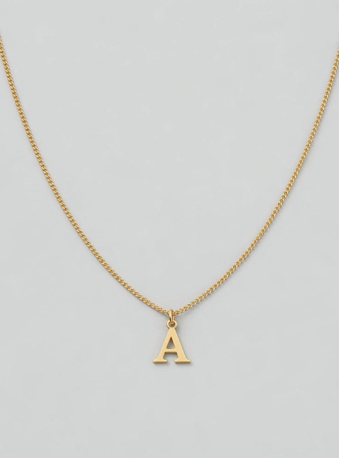 Gold necklace with a 'A' pendant on a light gray background