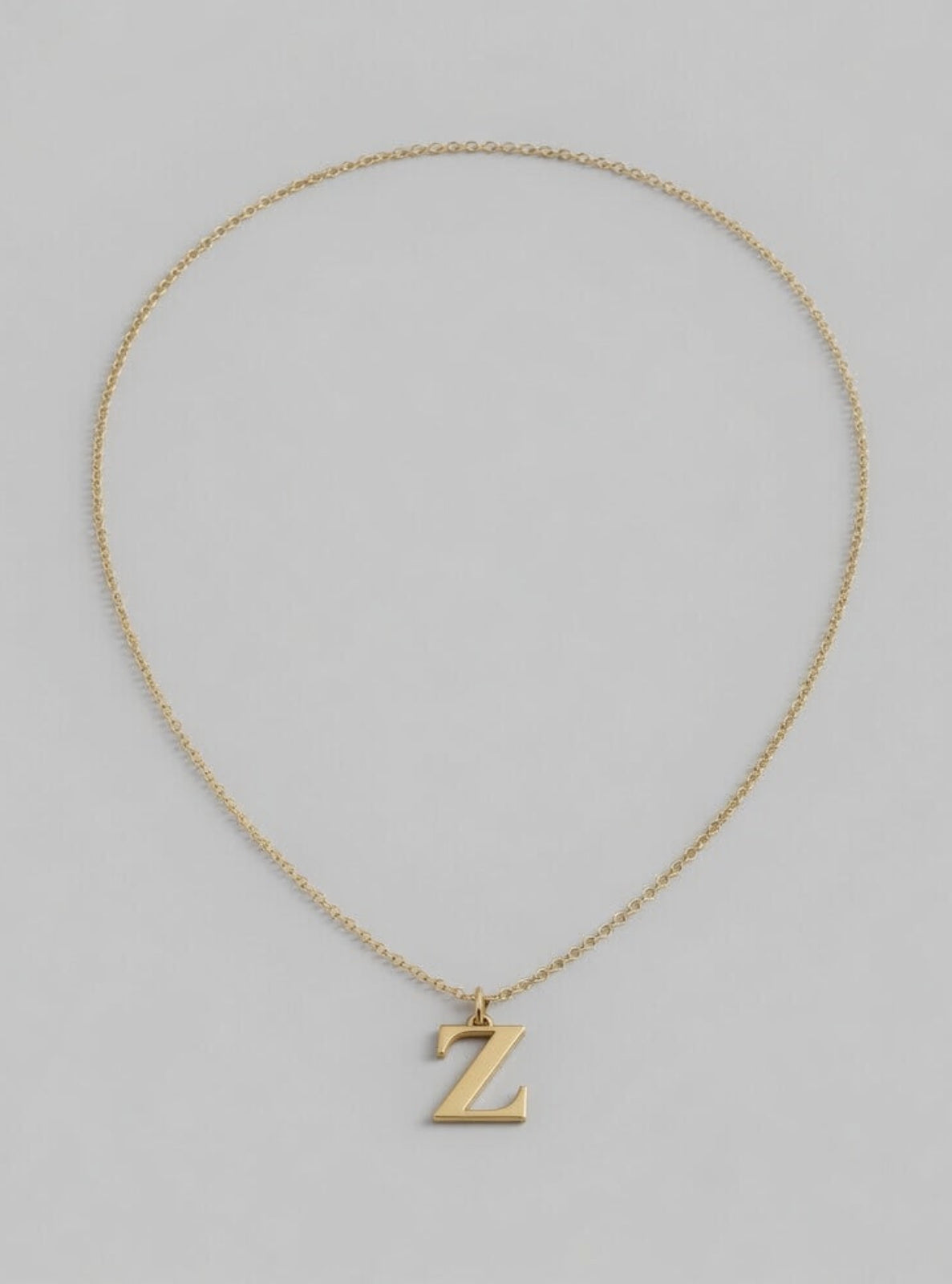 Gold necklace with a 'Z' pendant on a light gray background