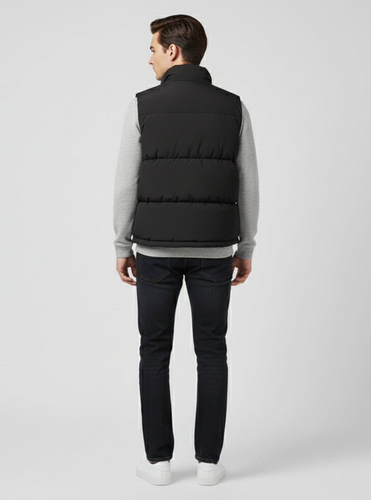Man wearing a black puffer vest on a light gray background