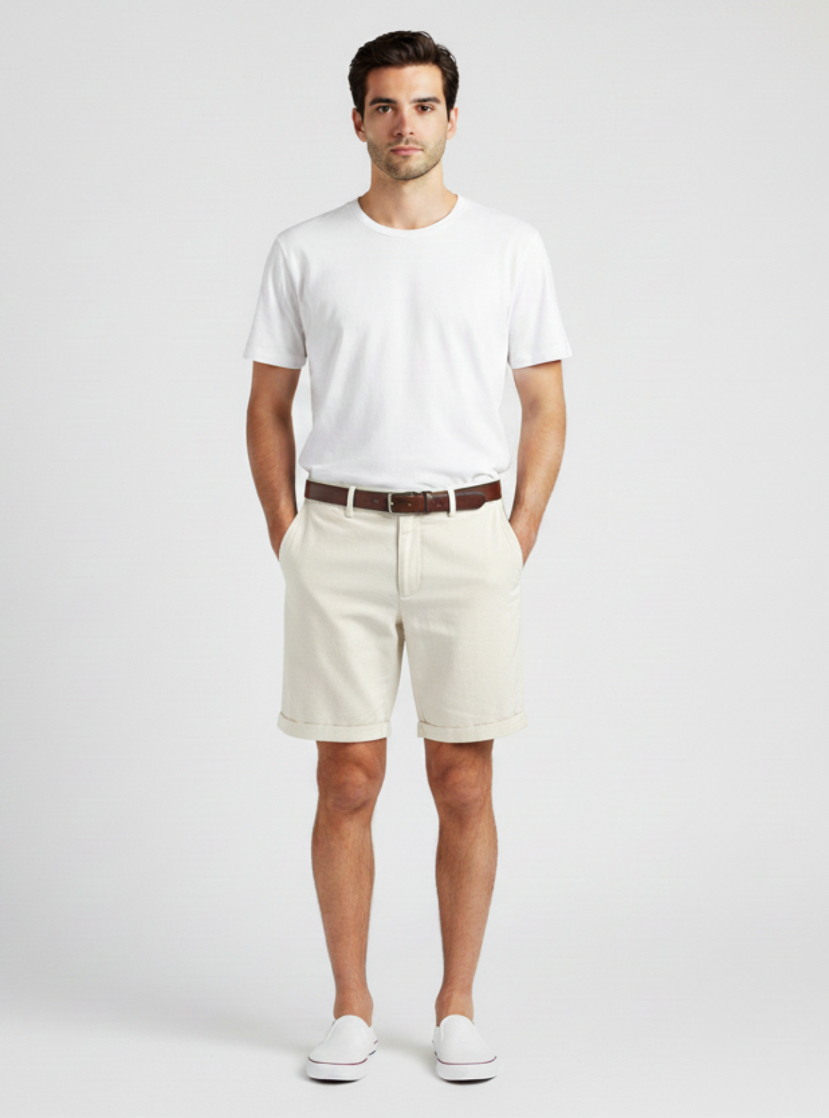 Man wearing a white t-shirt, beige shorts, and white sneakers on a plain background