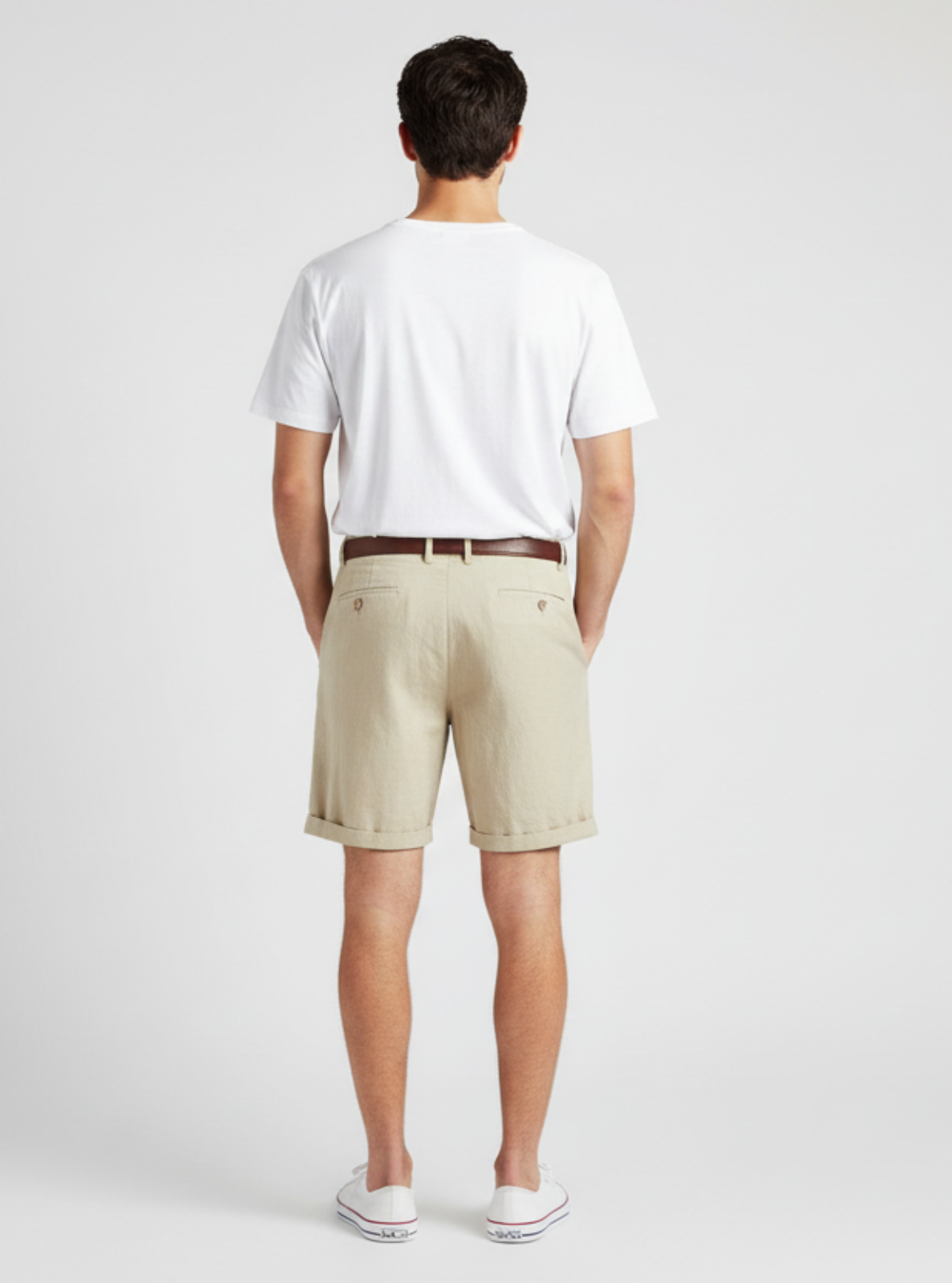 Person wearing a white shirt and beige shorts on a plain background